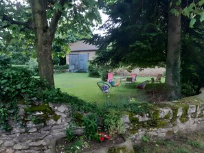 Un jardin avec un mur de pierre, une pelouse et du mobilier d’extérieur.