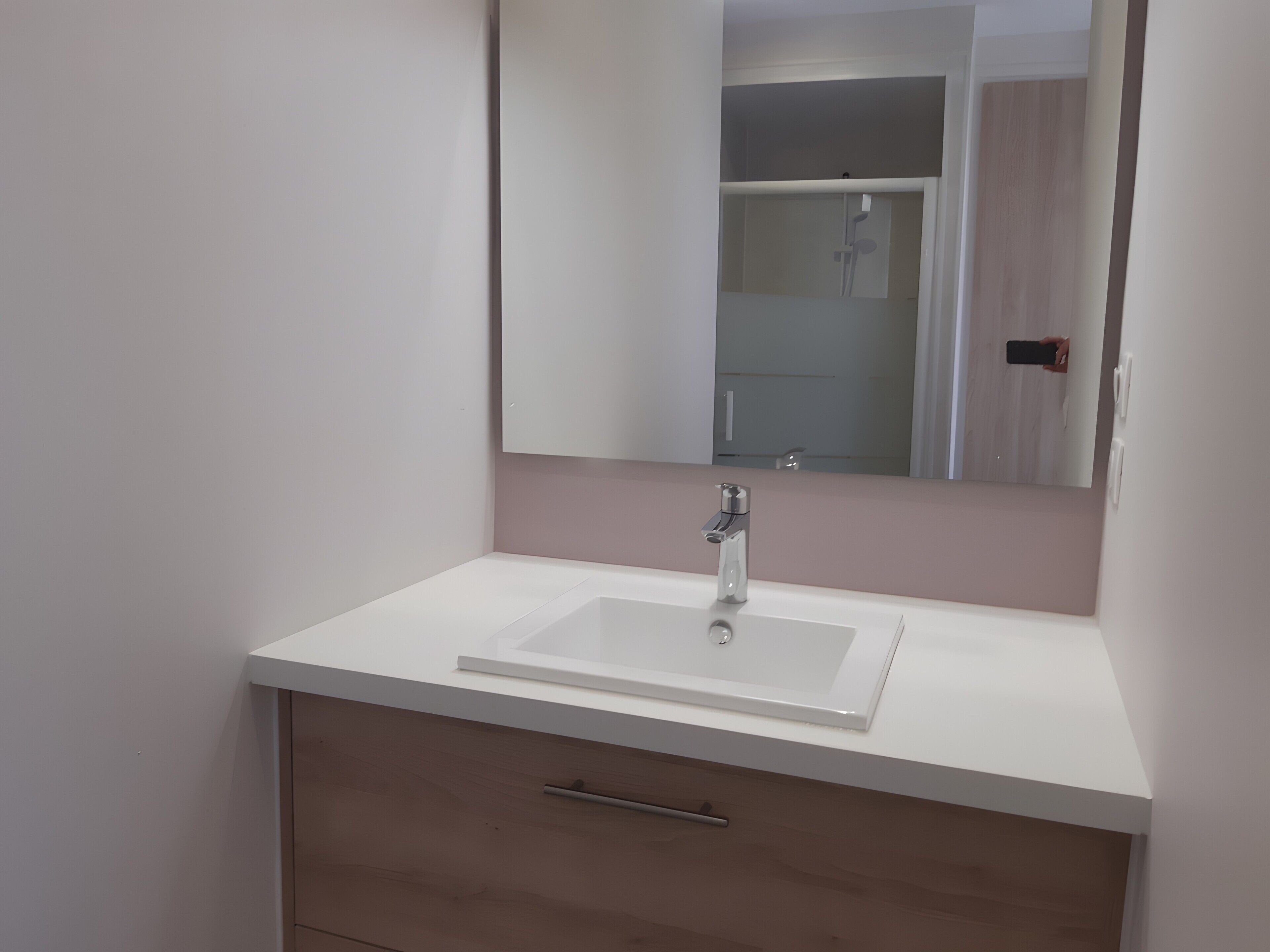 A bathroom with a white sink, a mirror, and a wooden cabinet.