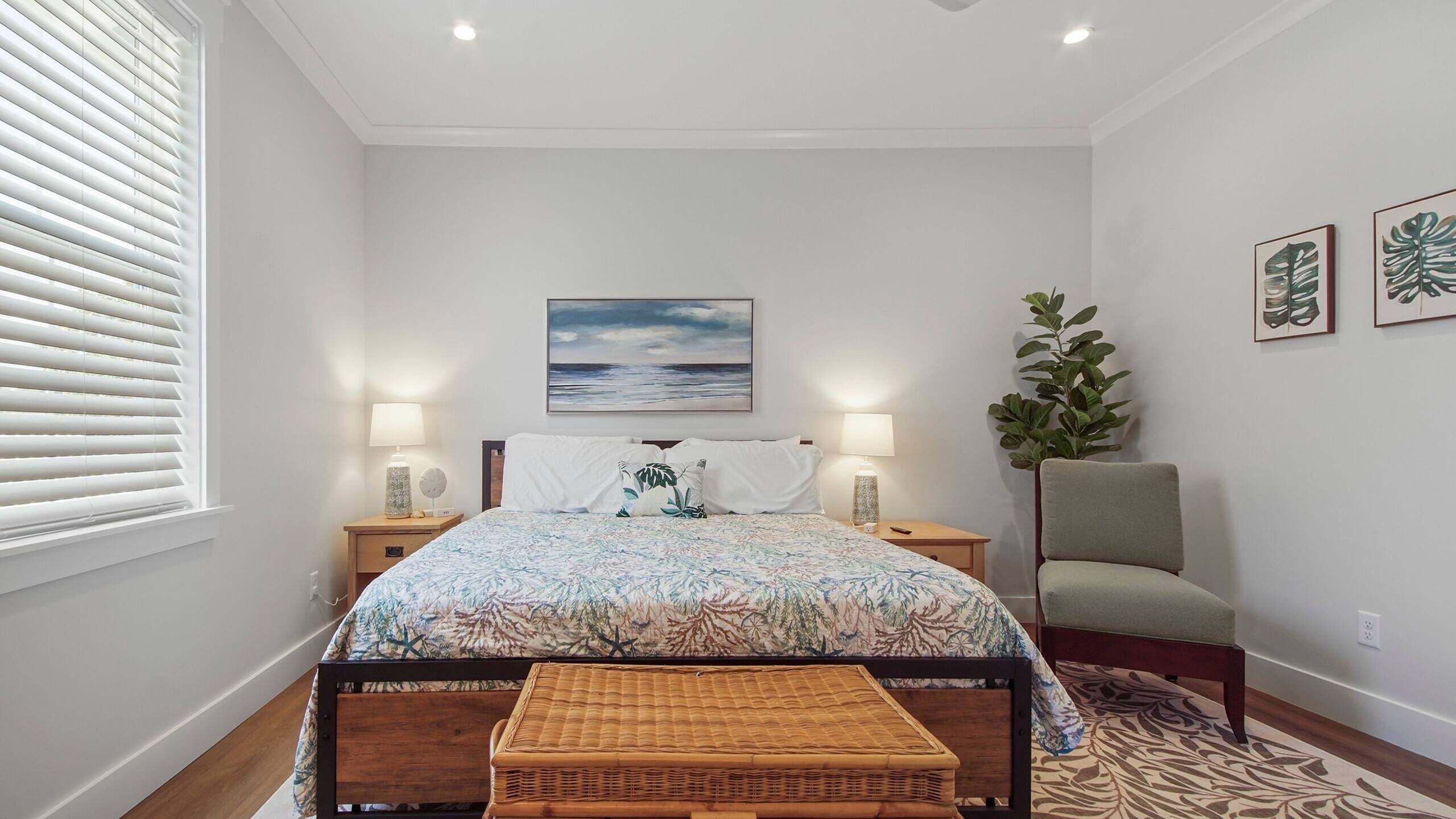 Quarto com cama, abajures, janela com persianas, um quadro, um vaso de planta e uma cadeira.