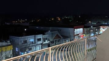 Uma varanda com grades de metal curvas voltada para uma área residencial à noite.