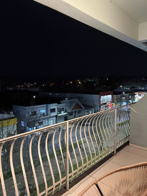 Balcó amb barana de metall corbada que dona a una zona residencial de nit.