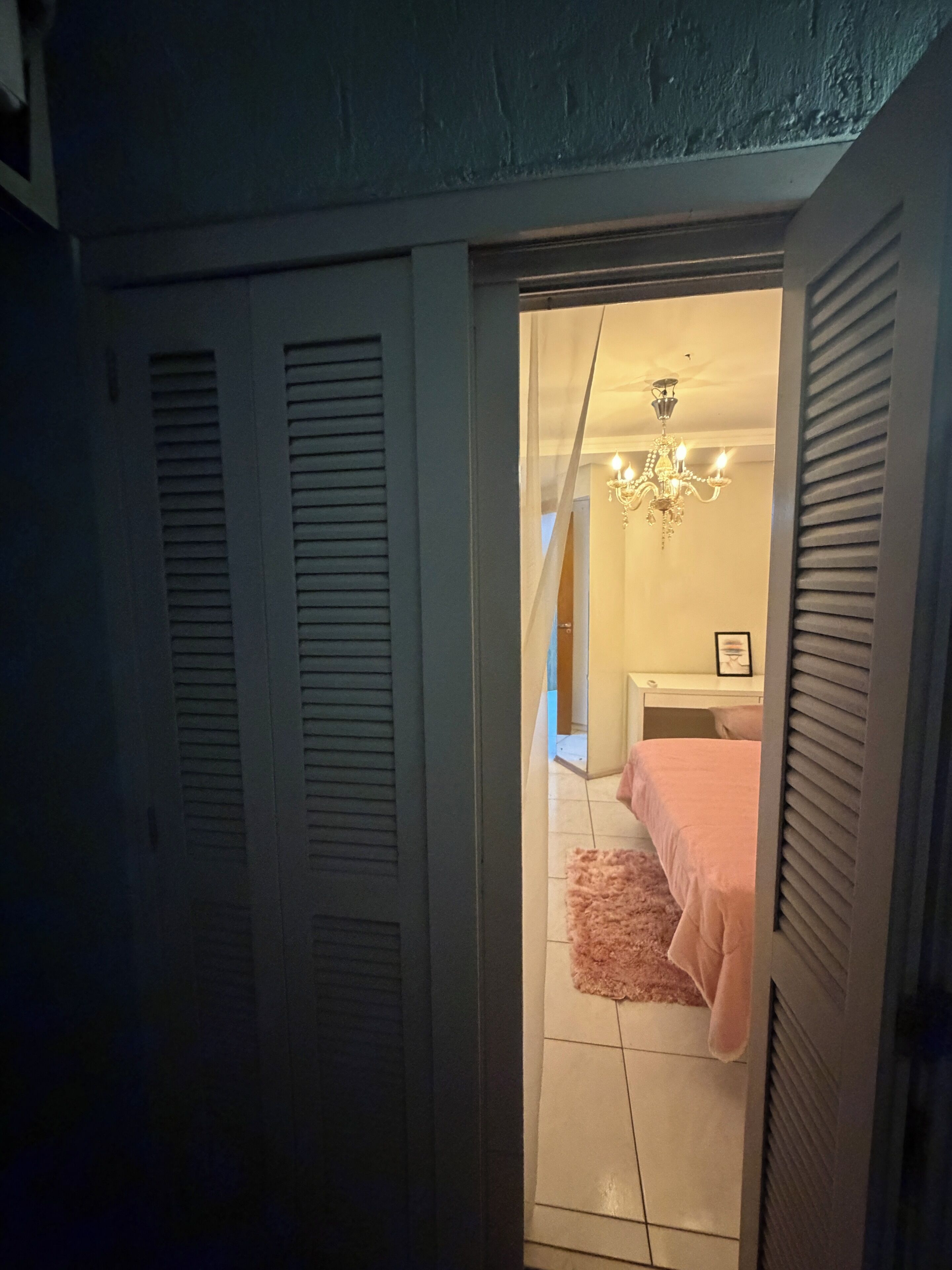 Ein Zimmer mit einem Bett, einer Chandelier und einer Tür zu einem weiteren Raum.