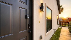 A modern house exterior with a dark grey door, a keypad lock, and a wall-mounted light fixture. - #10 | Clean Pet-Friendly Studio | Pool | Parking (South Padre Island)