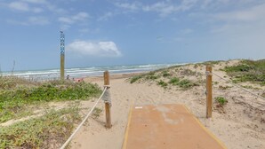 A sandy beach path leading to the ocean with a wooden post and rope barrier. - #10 | Clean Pet-Friendly Studio | Pool | Parking (South Padre Island)