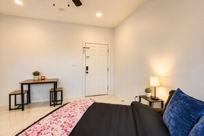A bedroom with a bed, a desk, a chair, a lamp, and a door. - #10 | Clean Pet-Friendly Studio | Pool | Parking (South Padre Island)