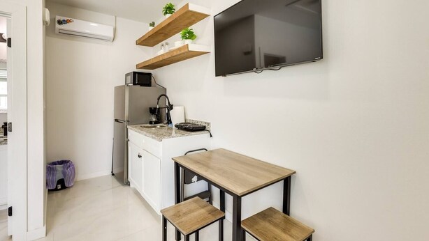 A compact kitchen with a built-in microwave, a coffee maker, and a small table with two stools. - #10 | Clean Pet-Friendly Studio | Pool | Parking (South Padre Island)
