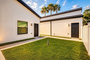 Une maison moderne à deux étages, dotée d’une pelouse bien entretenue, d’une porte de garage et d’un petit aménagement paysager.