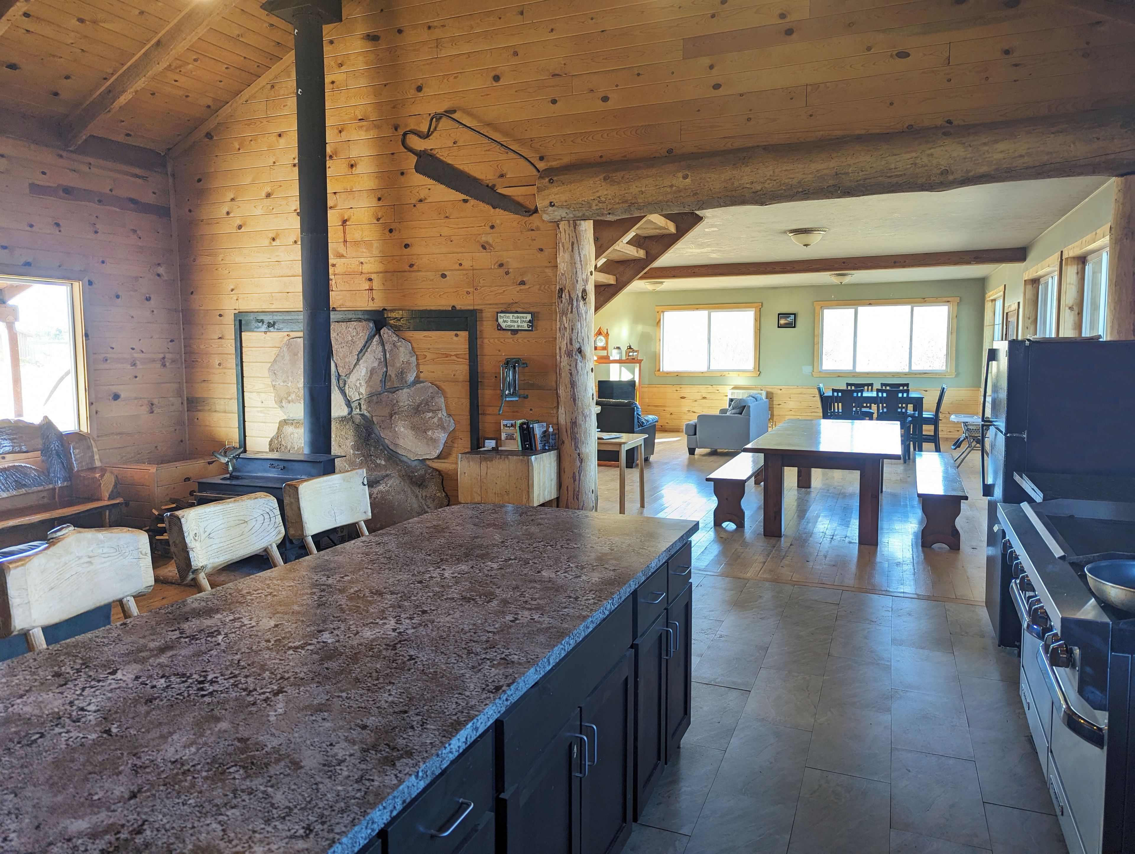 L’intérieur d’un chalet rustique comprend un coin cuisine, des murs en bois et une cheminée en pierre.