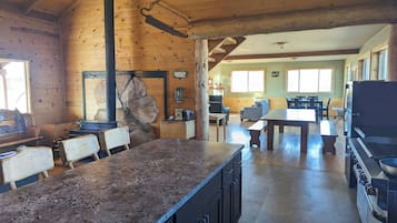 L’intérieur d’un chalet rustique comprend un coin cuisine, des murs en bois et une cheminée en pierre.