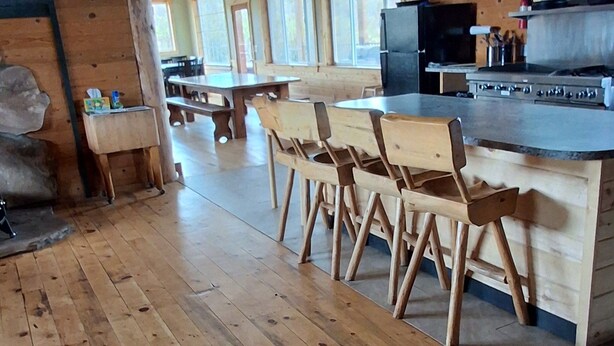 Un interior de madera con comedor, cocina y ventanas amplias.