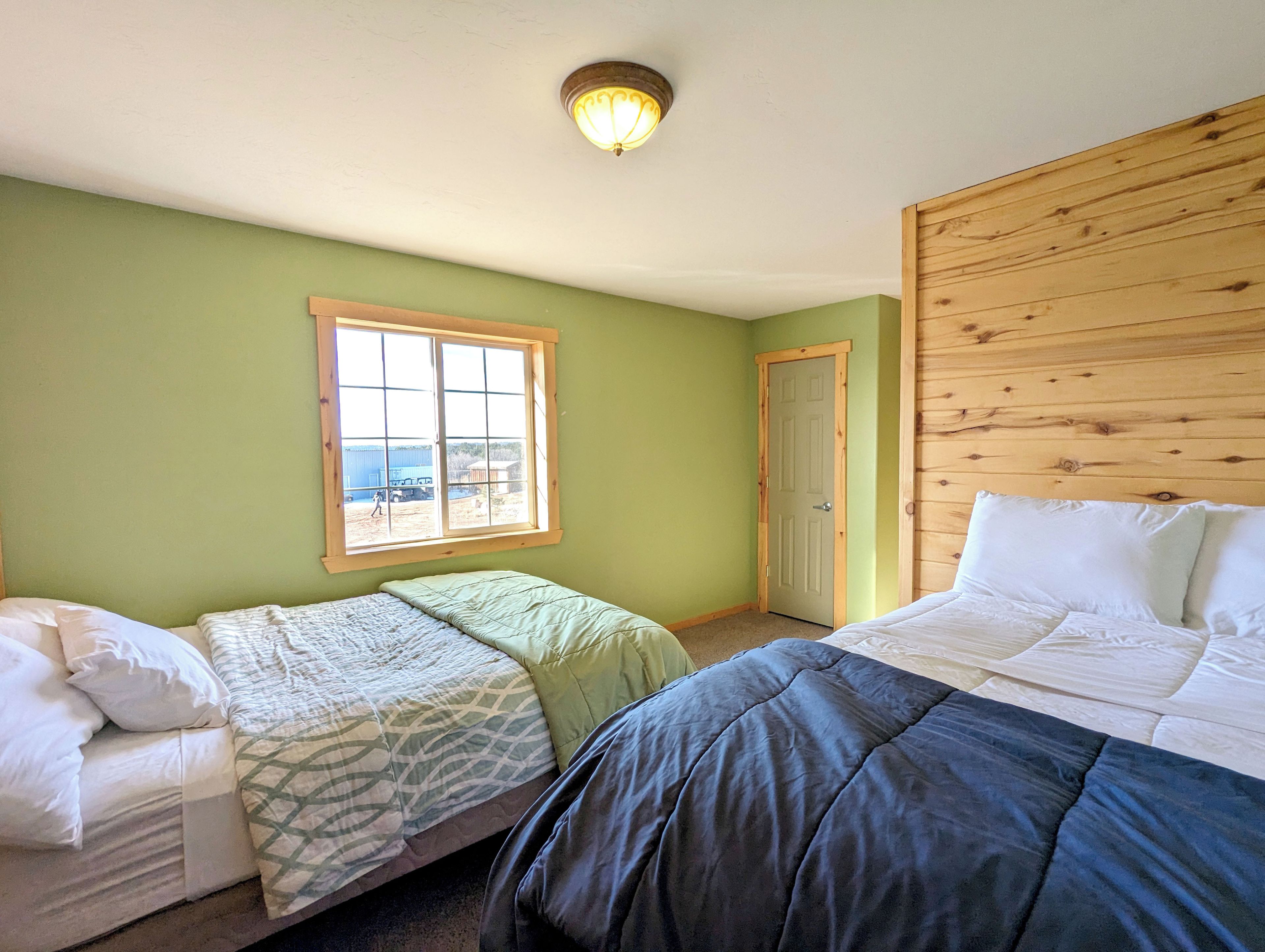 Une chambre avec deux lits, une fenêtre et une porte.