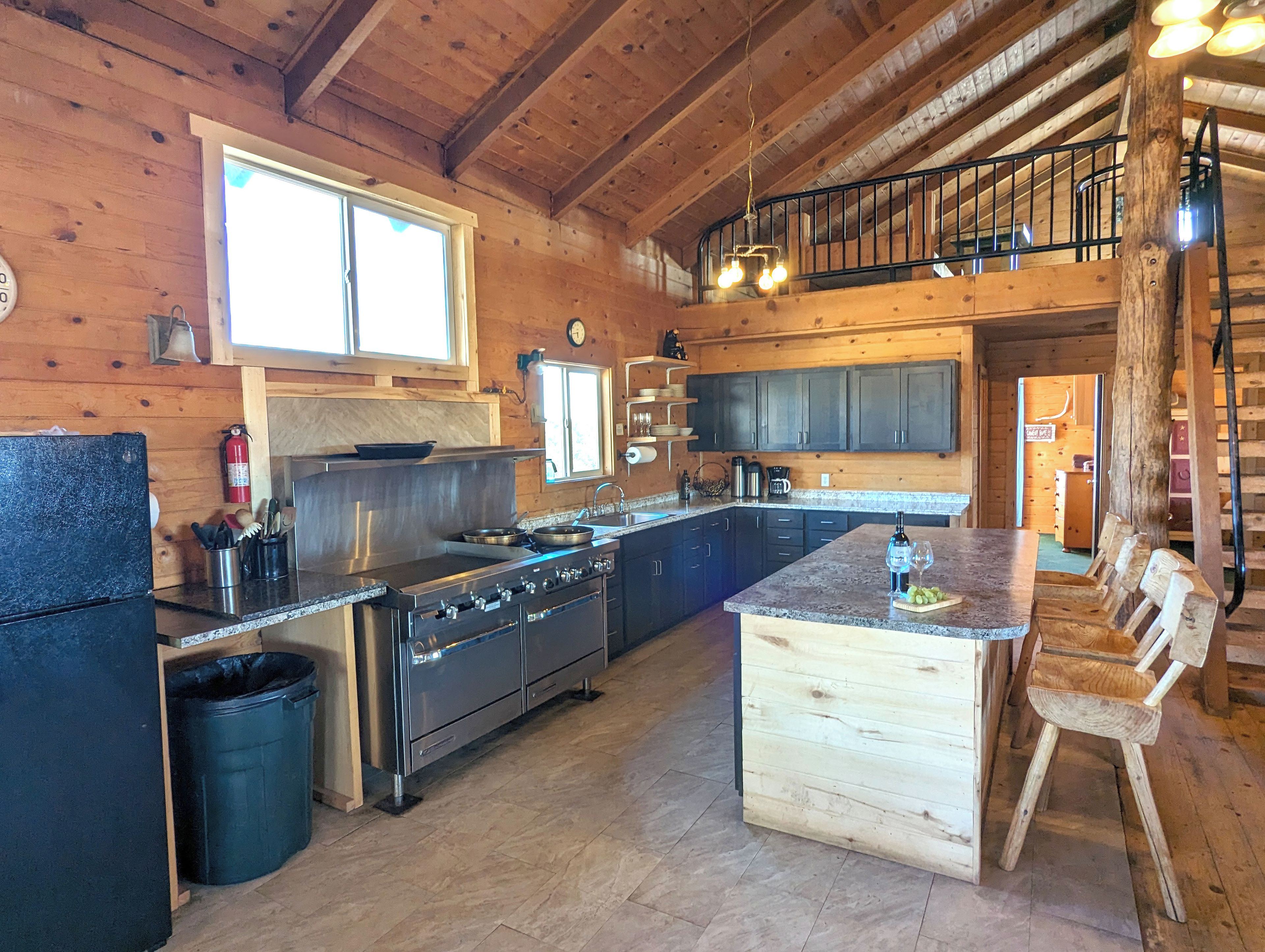Une cuisine spacieuse dotée d’un grand îlot central, de murs en bois et offrant une vue sur l’étage supérieur.