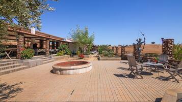 A patio with a fire pit, outdoor seating, and a statue.