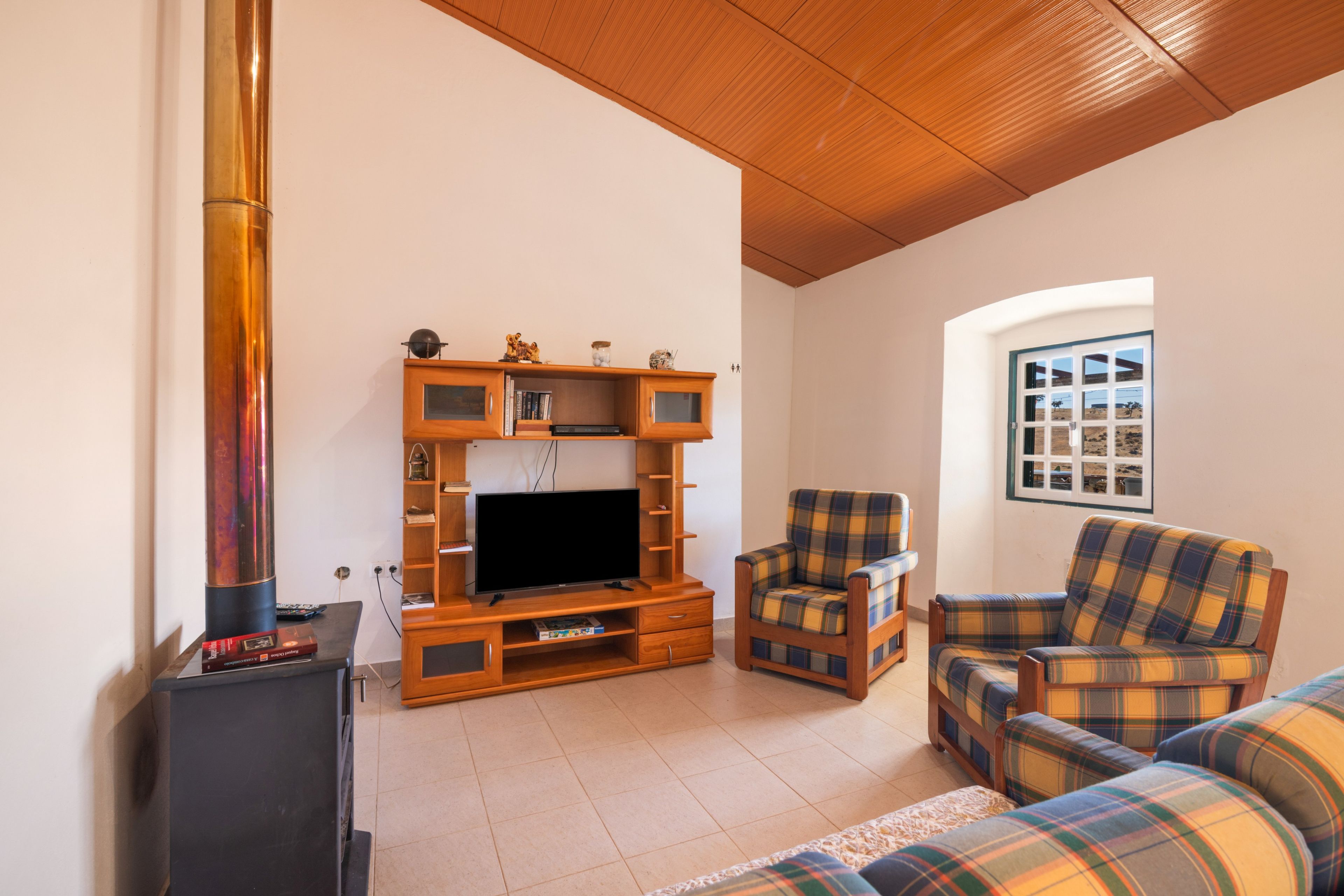 Una sala de estar con chimenea, televisor y muebles a cuadros.