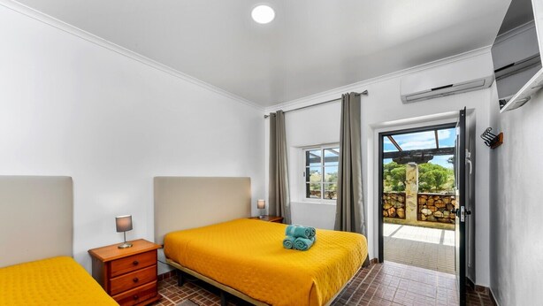 Habitación de hotel con cama, mesita de noche, lámpara y vistas al exterior.