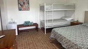 Habitación con literas, un escritorio, un banco y un cuadro colgado en la pared.