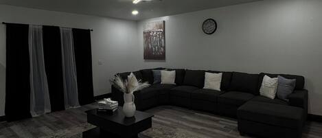 Un salon moderne avec un canapé d’angle, une table basse et un tapis.