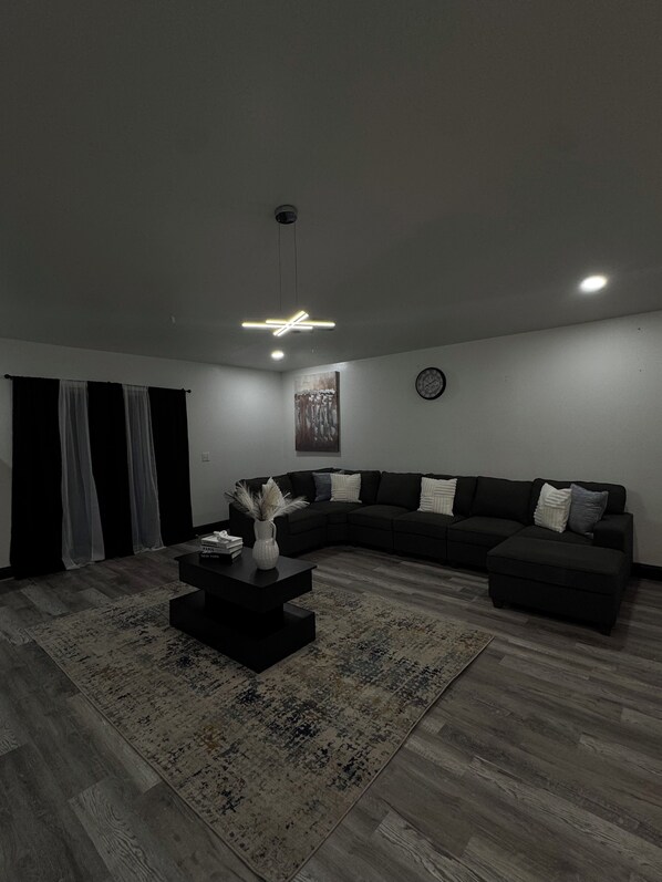 A modern living room with a sectional sofa, a coffee table, and a rug. - Remodeled 4BR Home– 2 FloorsExpansive Retreat 4BR 3.5BA Perfect for Groups (Ocala)