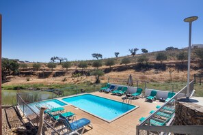 A swimming pool with lounge chairs and a view of a dry landscape.