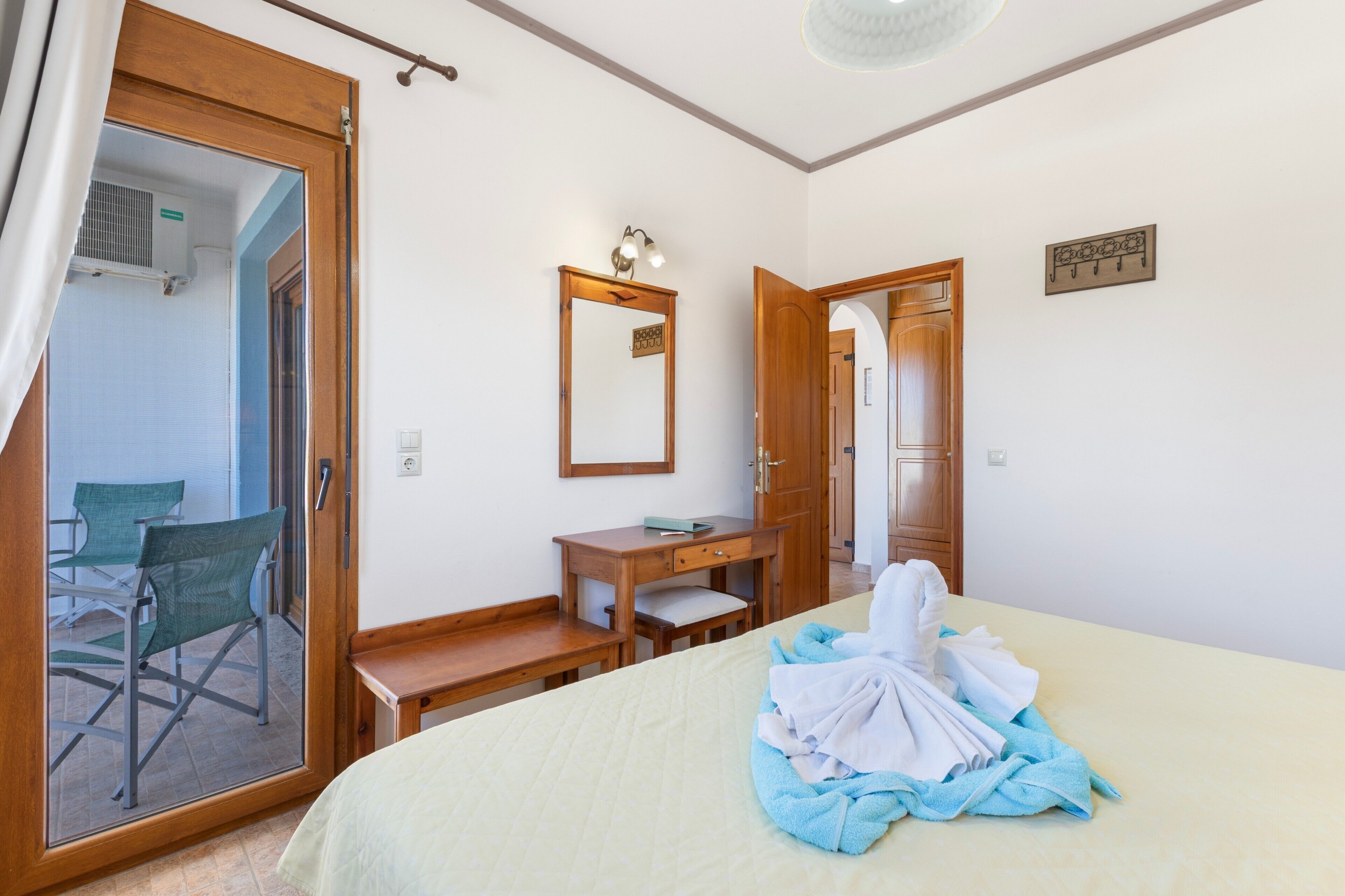 Ein Hotelzimmer mit einem Bett, einem Schreibtisch, einem Stuhl, einem Spiegel und einer Tür zu einem weiteren Raum.