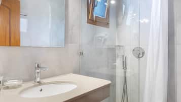 Une salle de bain moderne avec une douche à parois de verre, un lavabo doté d’un robinet chromé et un miroir au-dessus du lavabo.