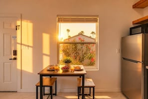 Eine Küche mit Fenster, Kühlschrank und einem Tisch mit Frühstücksgebäck.