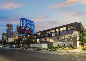 A modern hotel with a flat roof, multiple floors, and a prominent billboard. - Two Bedroom with Balcony & Laundry at Placemakr | Downtown Austin Stay (Austin)