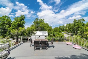 A rooftop terrace with a table and chairs, surrounded by a railing, and overlooking a lush green landscape. - La Holly Rooftop Retreat (Austin)