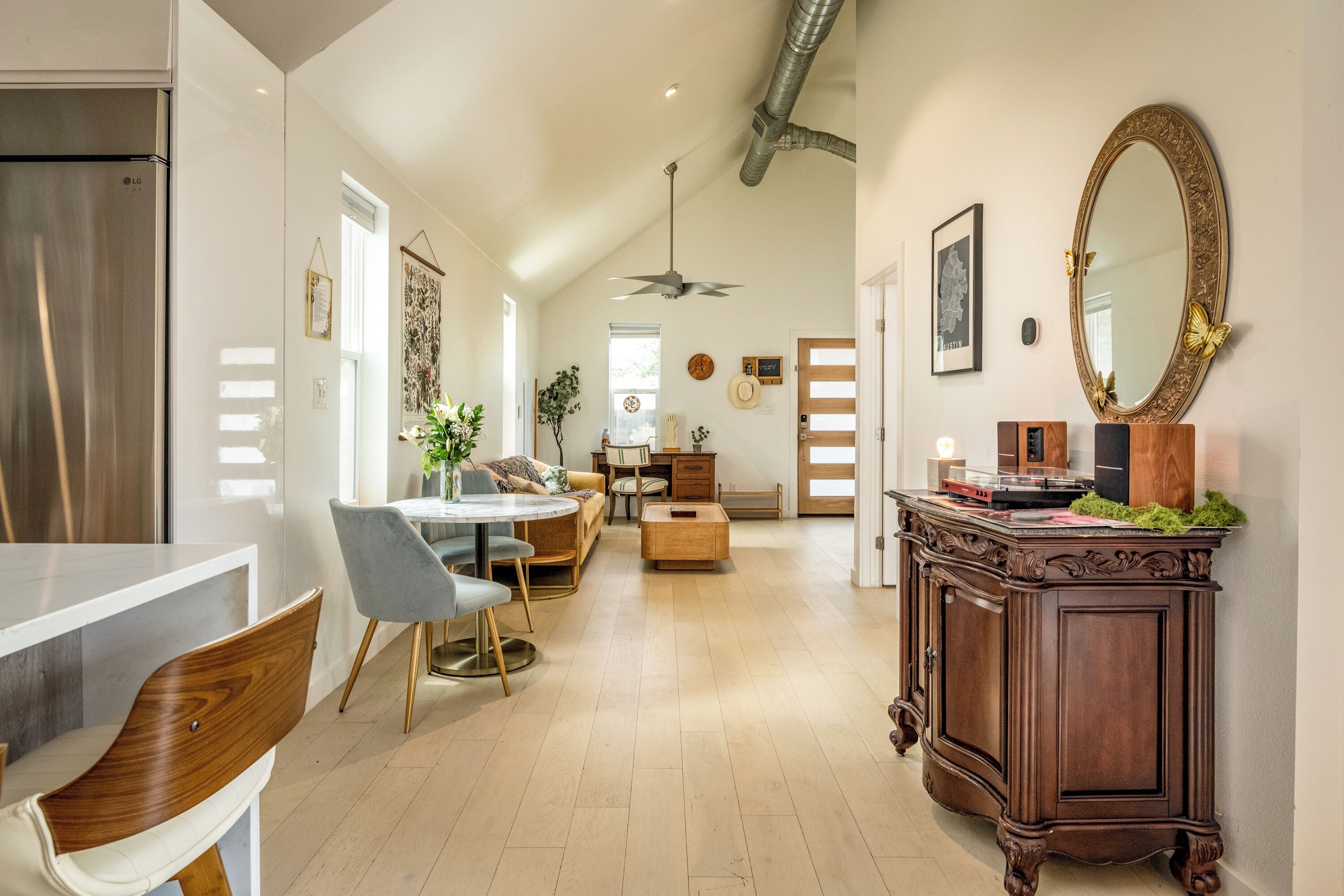 A spacious kitchen with a dining area, a large mirror, and a ceiling fan.