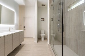 A modern bathroom with a glass-enclosed shower, a large mirror, and a toilet. - La Holly Rooftop Retreat (Austin)