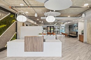 A modern office space with a reception desk, seating area, and a green wall. - Family-Friendly Room in Austin Downtown | Onsite Pool & Parking (Austin)