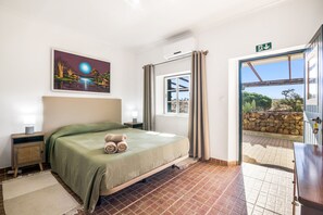 A hotel room with a bed, a painting, a window with curtains, and a view of the outside. - Apartment 'Quarto 1' with Wi-Fi and Air Conditioning (Corte do Pinto)