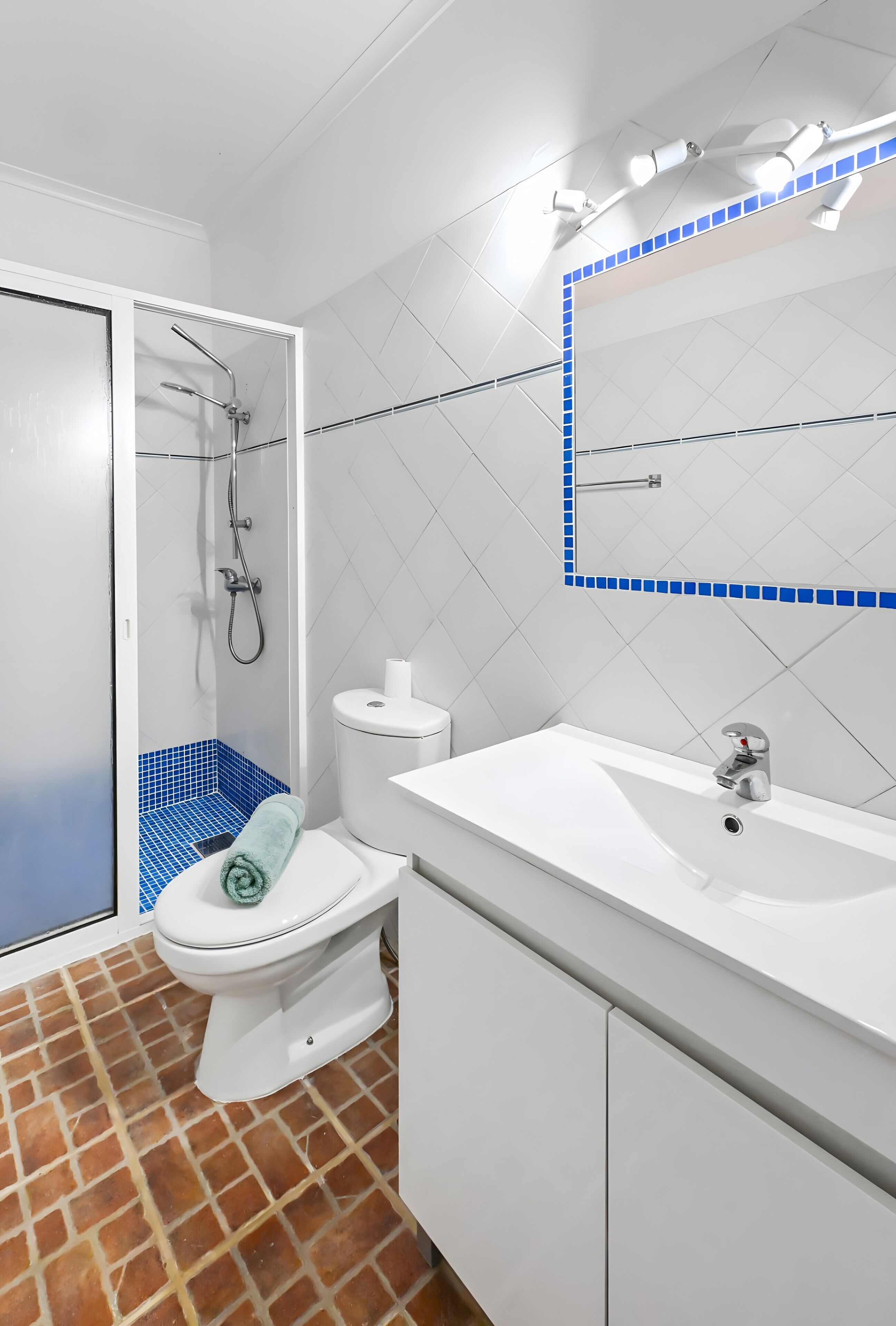 Ein Badezimmer mit Toilette, Dusche, Waschbecken und Spiegel.