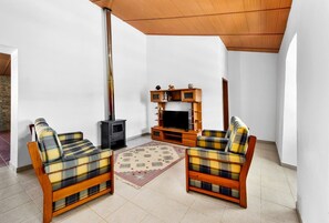 Ein Wohnzimmer mit zwei karierten Sofas, einem Fernseher, einer Holz-Unterhaltungseinheit und einem Kaminofen.