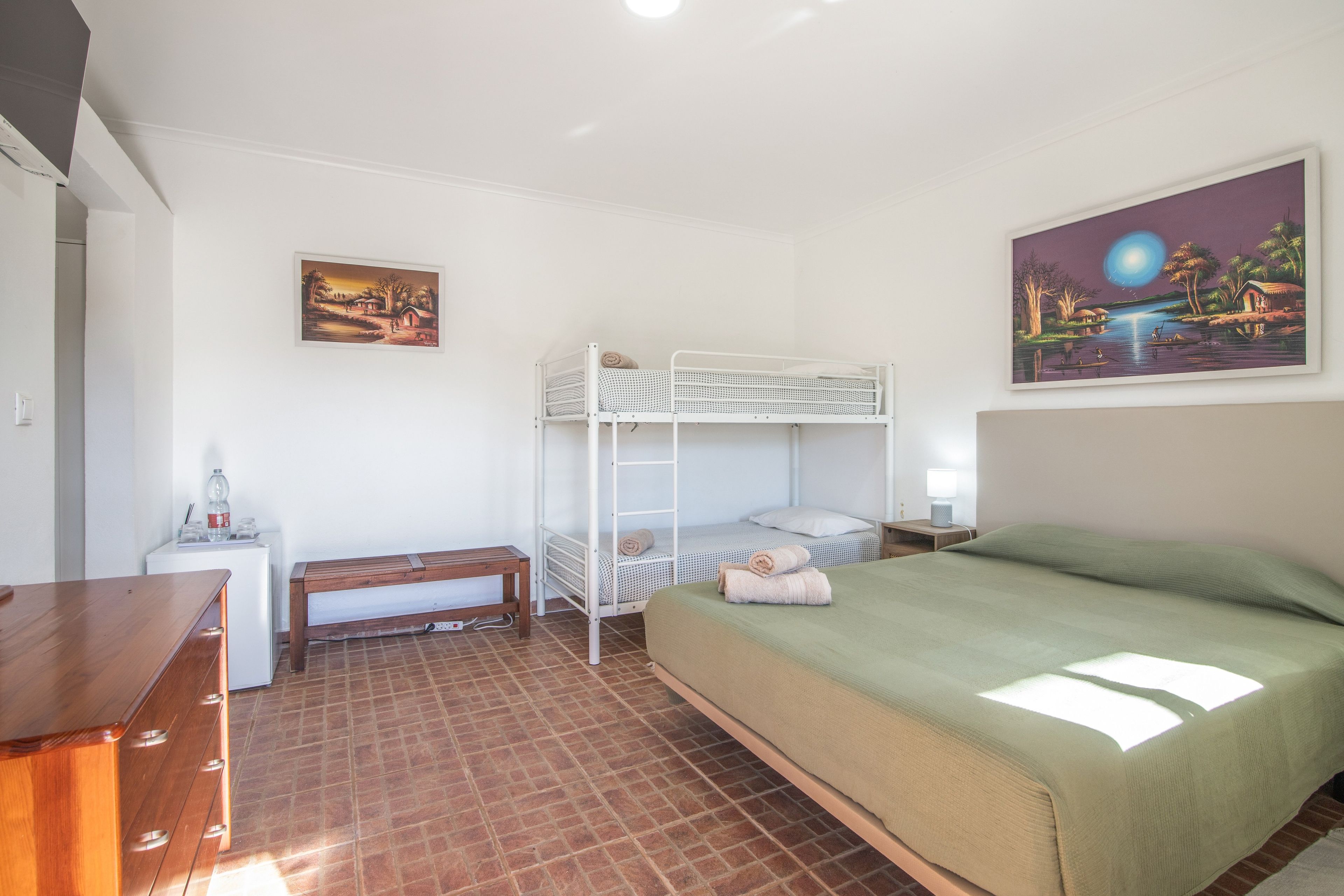 Une chambre avec un lit superposé, un bureau, une chaise, une petite table et un tableau accroché au mur.