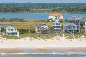 A beachfront property with multiple houses, a beach, and a lake in the background. - Oceanfront cottage with crow’s nest (North Topsail Beach)