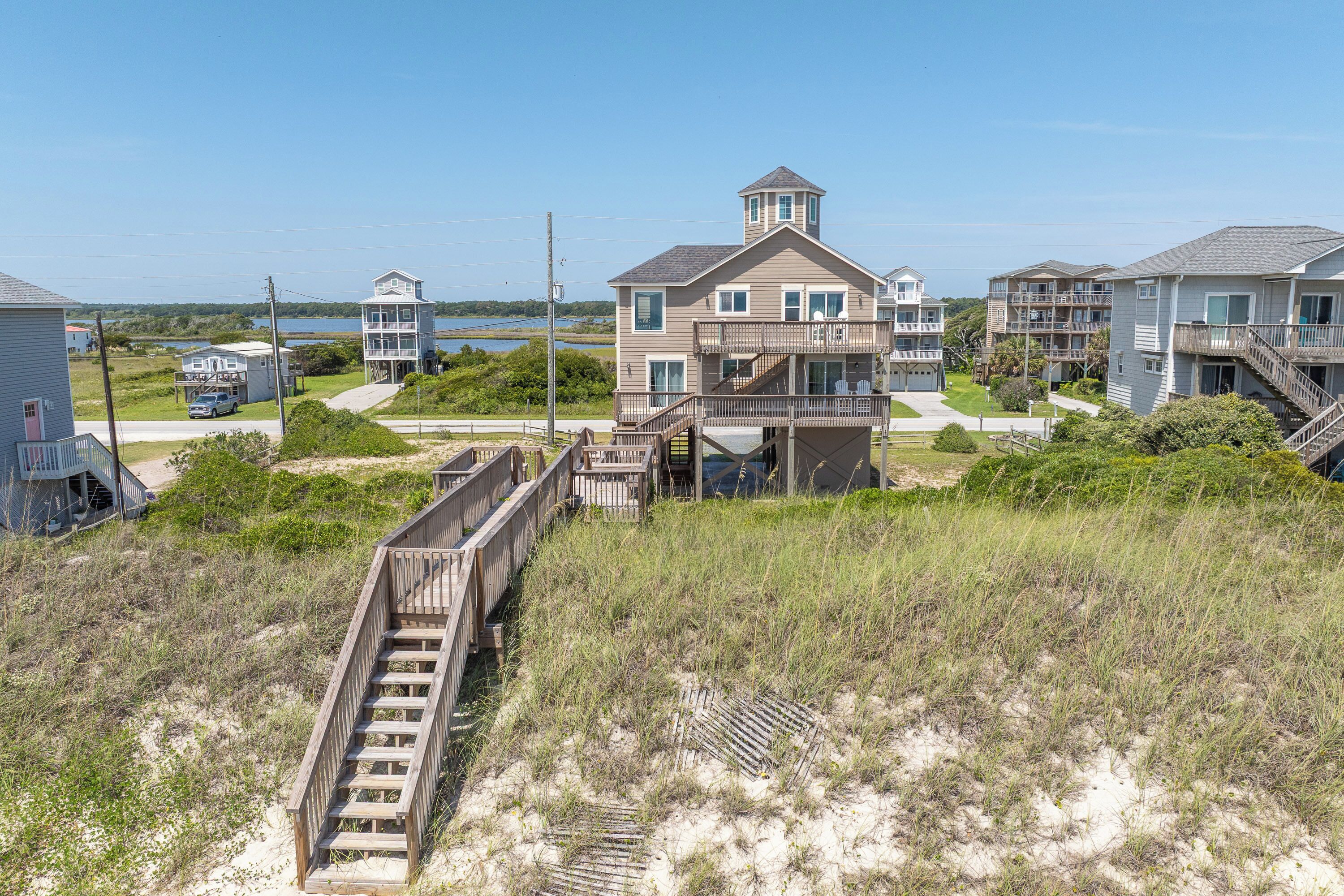 Un quartier résidentiel situé sur la côte, avec des maisons, une promenade en bois et une vue sur la mer.