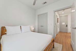 A bedroom with a bed, a nightstand, a door, and a hallway leading to another room. - Premium One bedroom Unit | Downtown Austin Stay | Near 3rd Street | Pool access (Austin)
