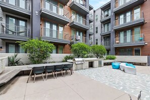 A modern apartment complex with outdoor seating areas, a barbecue grill, and a patterned patio. - Modern Room with Private Balcony + Pool view! | Near Museums (Austin)