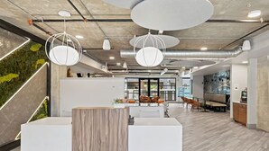 Et moderne kontormiljø med en receptionsdisk, siddeområde og en grøn væg.