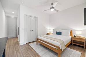 A bedroom with a bed, bedside tables, a ceiling fan, and a door. - Premium Studio Balcony room | Near E 3rd St Attractions + Pool access! (Austin)