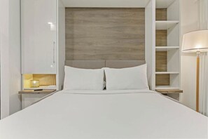 A modern bedroom with a wooden headboard, white bedding, and built-in shelving. - Premium Studio Apartment stay at Placemakr Downtown Austin | Near East 3rd St (Austin)