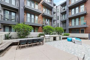 A modern apartment complex with outdoor seating areas, a barbecue grill, and a patterned patio. - Premium Studio Apartment stay at Placemakr Downtown Austin | Near East 3rd St (Austin)