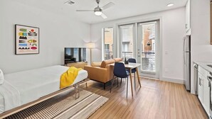 Et moderne hotelværelse med seng, skrivebord, stol, lampe og loftsvift.