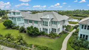 A large, multi-story house with a prominent balcony and a well-maintained lawn. - DOMINICA ISLES 201 | Luxury Retreat at Isles of Collier Preserve (Naples)