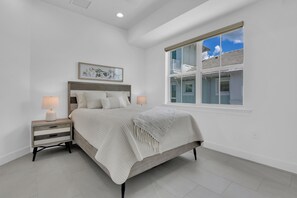 A bedroom with a bed, bedside tables, a window, and a ceiling light. - DOMINICA ISLES 201 | Luxury Retreat at Isles of Collier Preserve (Naples)