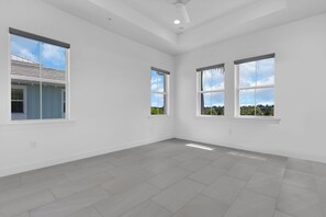 A spacious, empty room with large windows and a tiled floor. - DOMINICA ISLES 201 | Luxury Retreat at Isles of Collier Preserve (Naples)