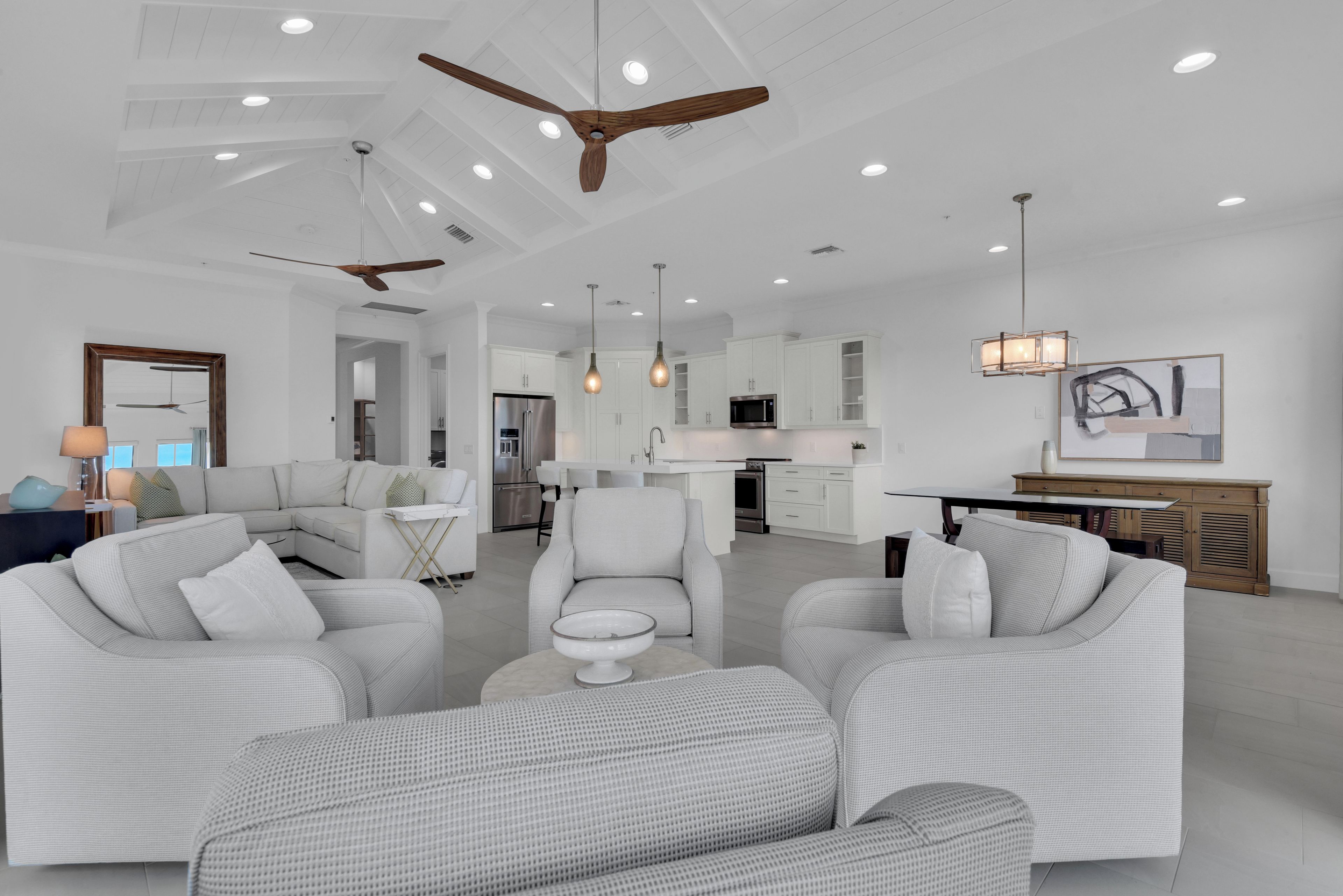 A modern living room with a sofa set, a dining area, and a kitchen with white cabinetry.