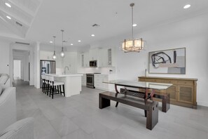A modern kitchen with white cabinetry, stainless steel appliances, and a central island. - DOMINICA ISLES 201 | Luxury Retreat at Isles of Collier Preserve (Naples)