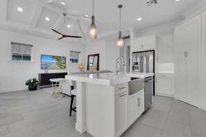 A modern kitchen with a central island, stainless steel appliances, and a ceiling fan. - DOMINICA ISLES 201 | Luxury Retreat at Isles of Collier Preserve (Naples)
